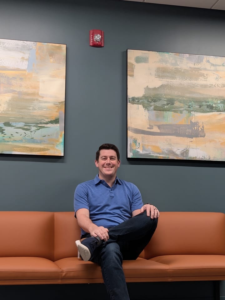 Will Elnick smiling while seated in an office lounge